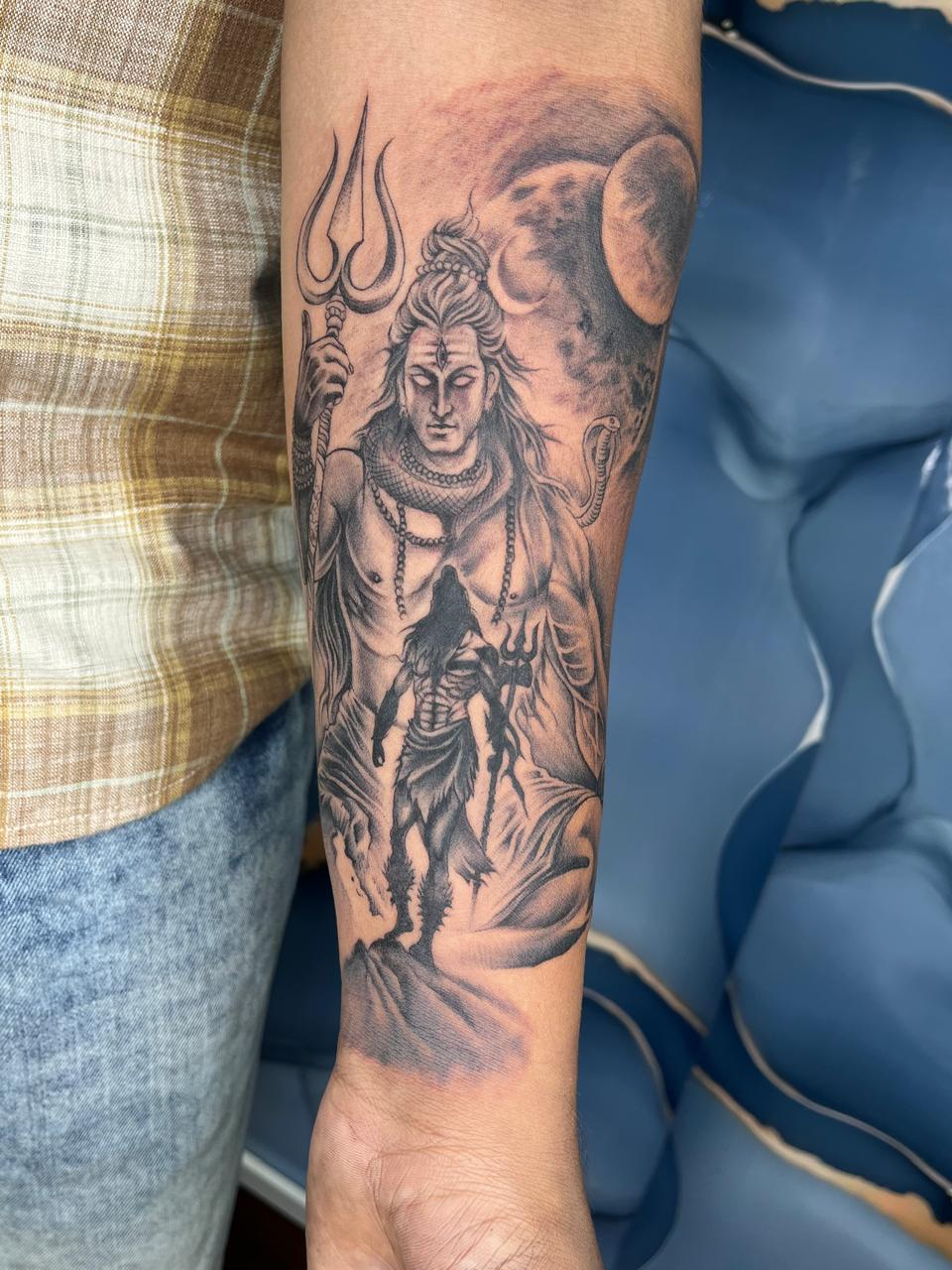 Large-scale Lord Shiva forearm tattoo in black and grey shading with trishul and crescent moon at Evil Tattoo Studio, Madhapur, Hyderabad
